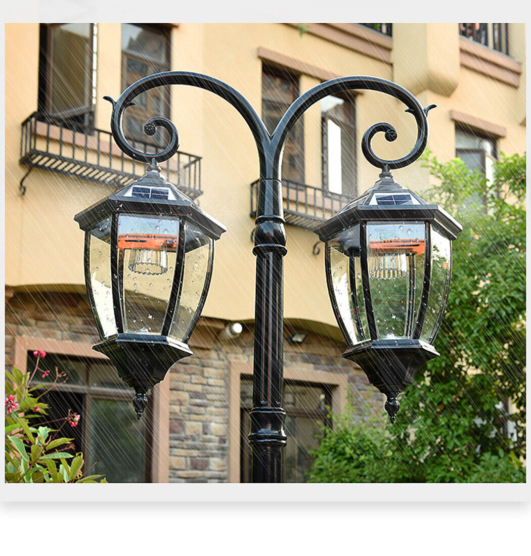 Black solar street light with dual lantern heads mounted on a decorative pole, each lantern featuring clear glass panels. The light stands 230 cm tall, Ideal for outdoor use in streets, gardens, or pathways.