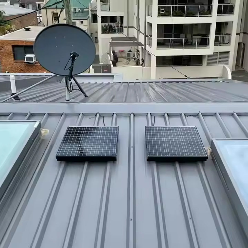 Metal rooftop with dual solar panels powering round solar skylight system, positioned beside a satellite dish and adjacent to skylight glass panels—highlighting integrated renewable energy and communication technology.