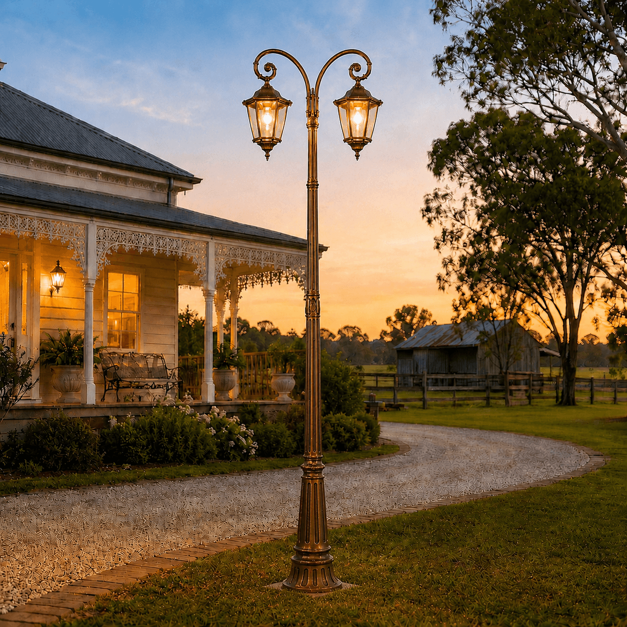 Antique bronze double head solar post light glowing at dusk alongside a rural driveway and heritage home.