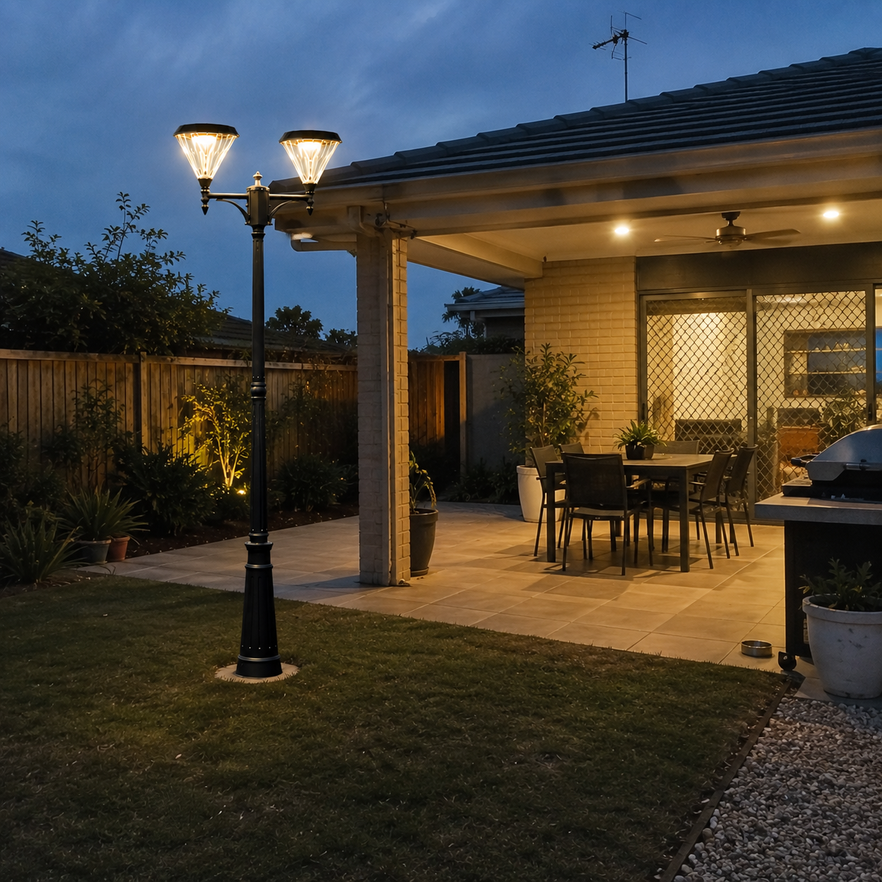 Double head flat top solar street light casting a warm glow over an outdoor patio, backyard lawn, and alfresco dining area at night.