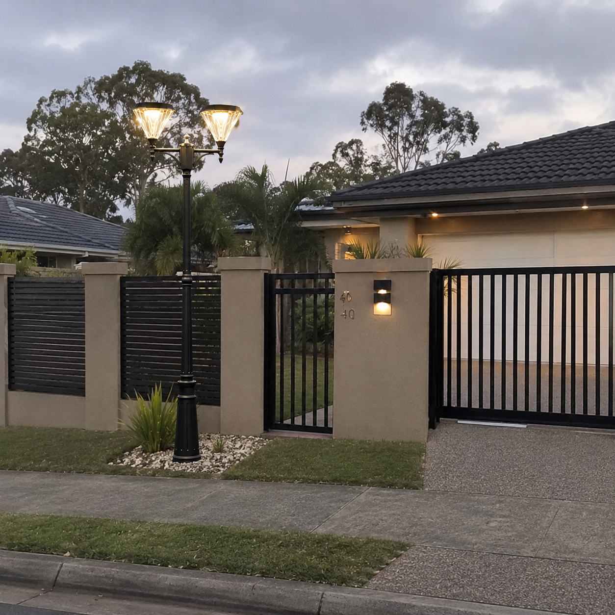 Double head solar pillar light illuminating a front gate, fence line, and entranceway of a suburban house property.