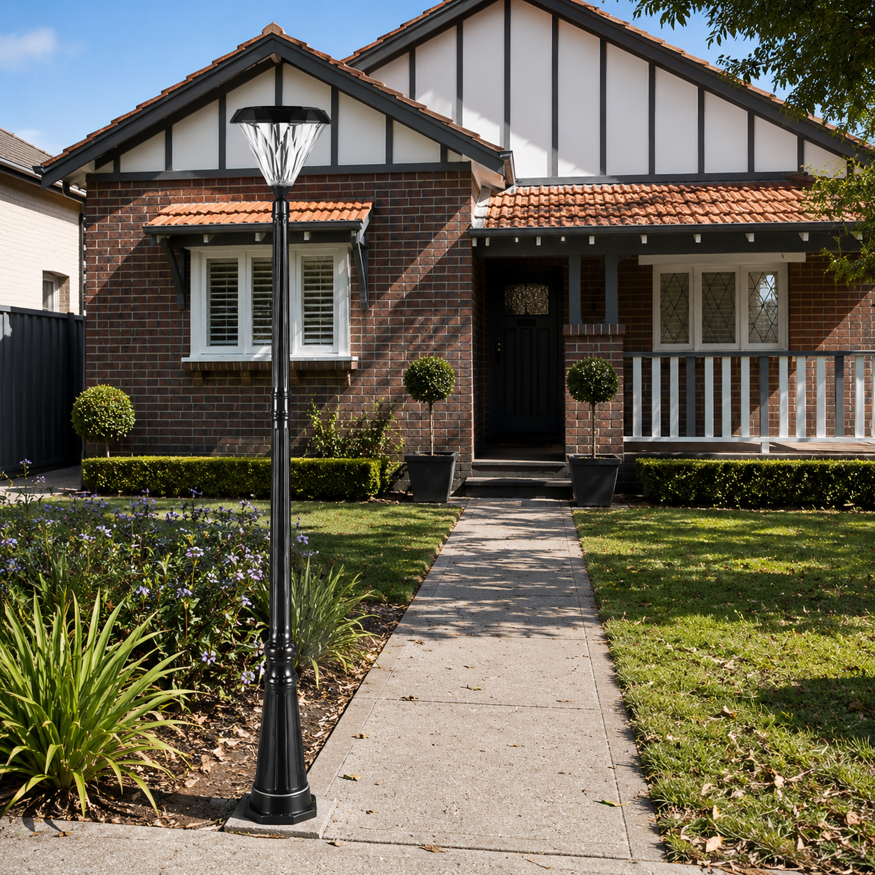 Modern flat top solar lantern installed next to a concrete pathway walkway leading to a traditional brick house in an australian front yard garden.