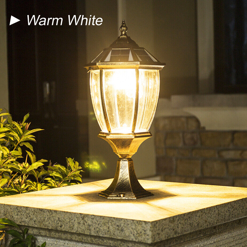 "A timeless bronze solar post lamp, featuring elegant clear glass panels that emit a soft warm white glow. Mounted on a sturdy stone base, this elegant light adds a touch of sophistication to any garden, beautifully framed by lush green foliage for a serene outdoor ambiance