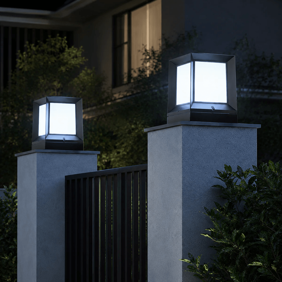 Two solar gate cap lights glowing in cool white mode at night mounted on concrete fence pillars at a home entrance