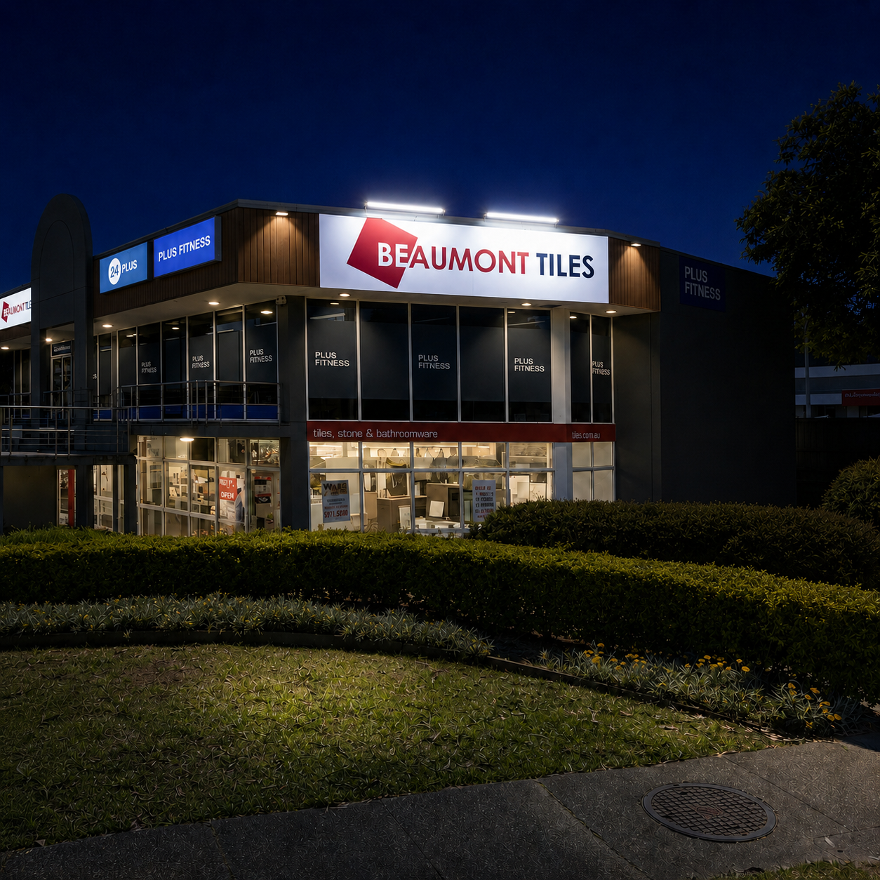 Multiple 120cm solar billboard light units are mounted along the roofline to brightly illuminate a large commercial showroom building fascia sign at night.