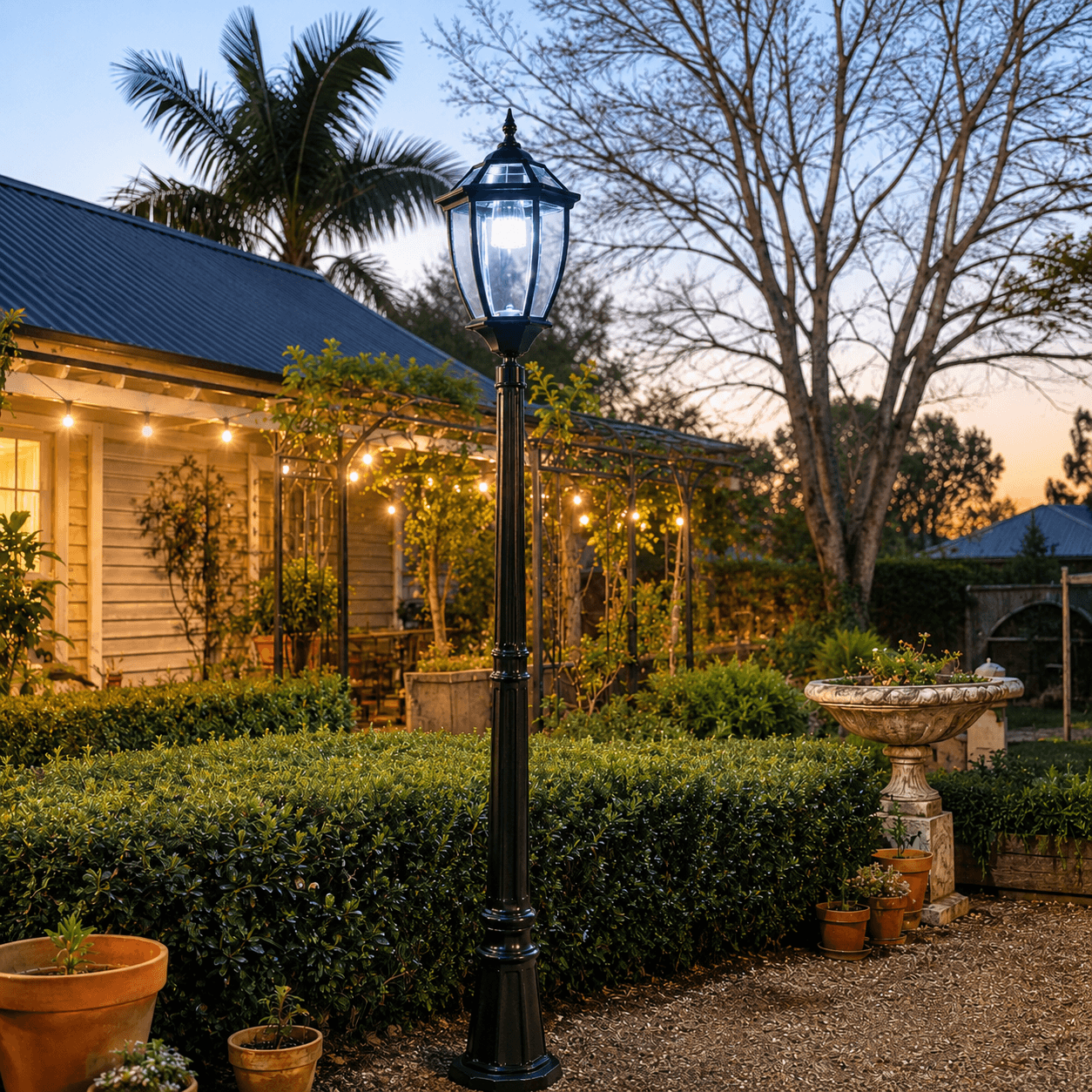An antique solar lantern style black solar post light outdoor fixture illuminating a rustic cottage garden yard at twilight in Australia.
