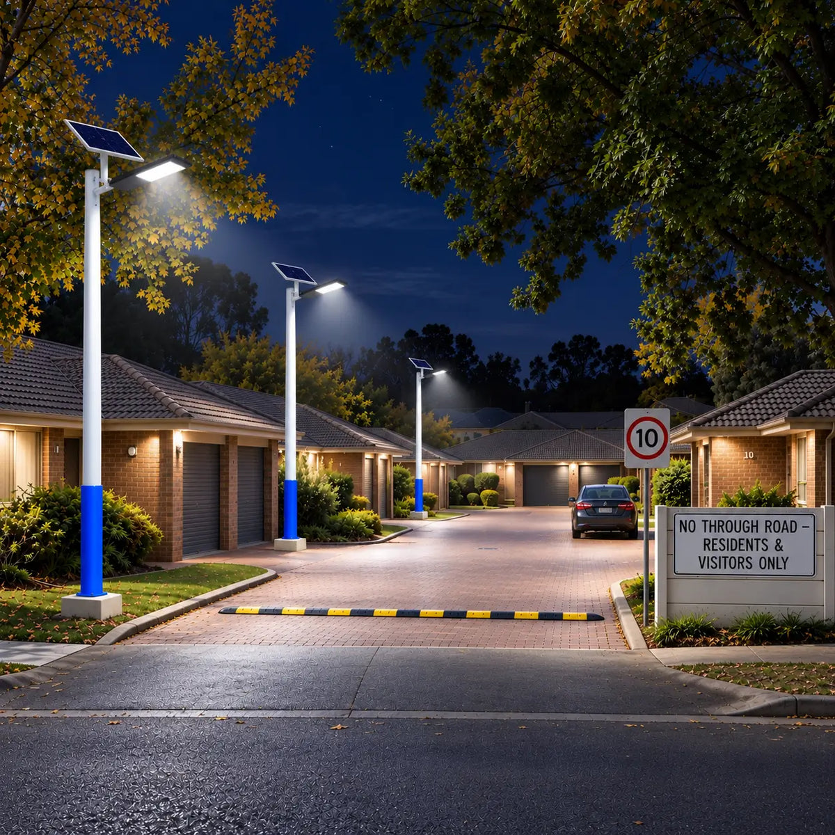 Multiple Rainman G90 commercial solar street lights brightly illuminating a paved private entry road and townhouse driveway layout at night, showcasing strata estate security lighting for residents.