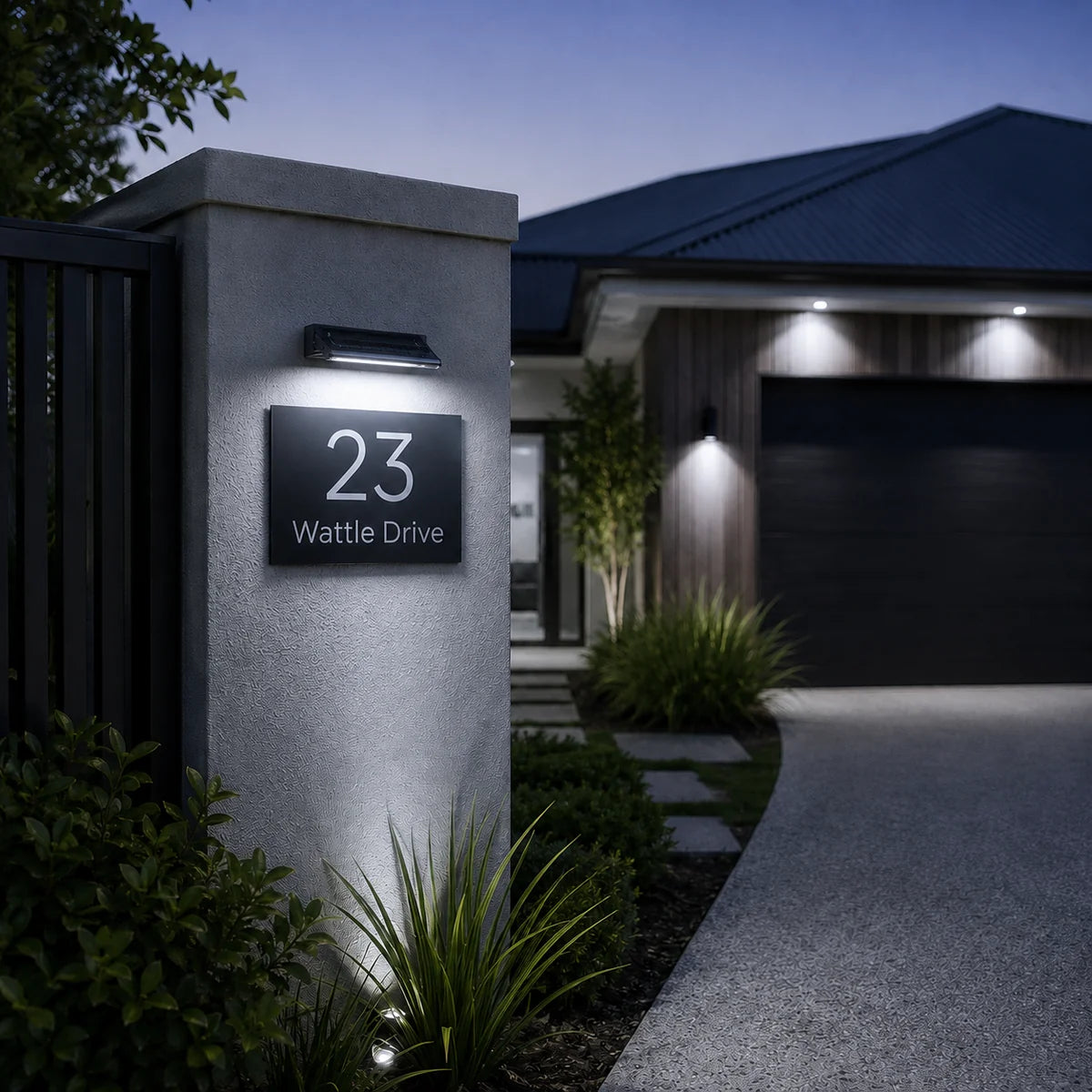 A solar powered sign light mounted on a concrete pillar illuminating a modern home address plate at night.