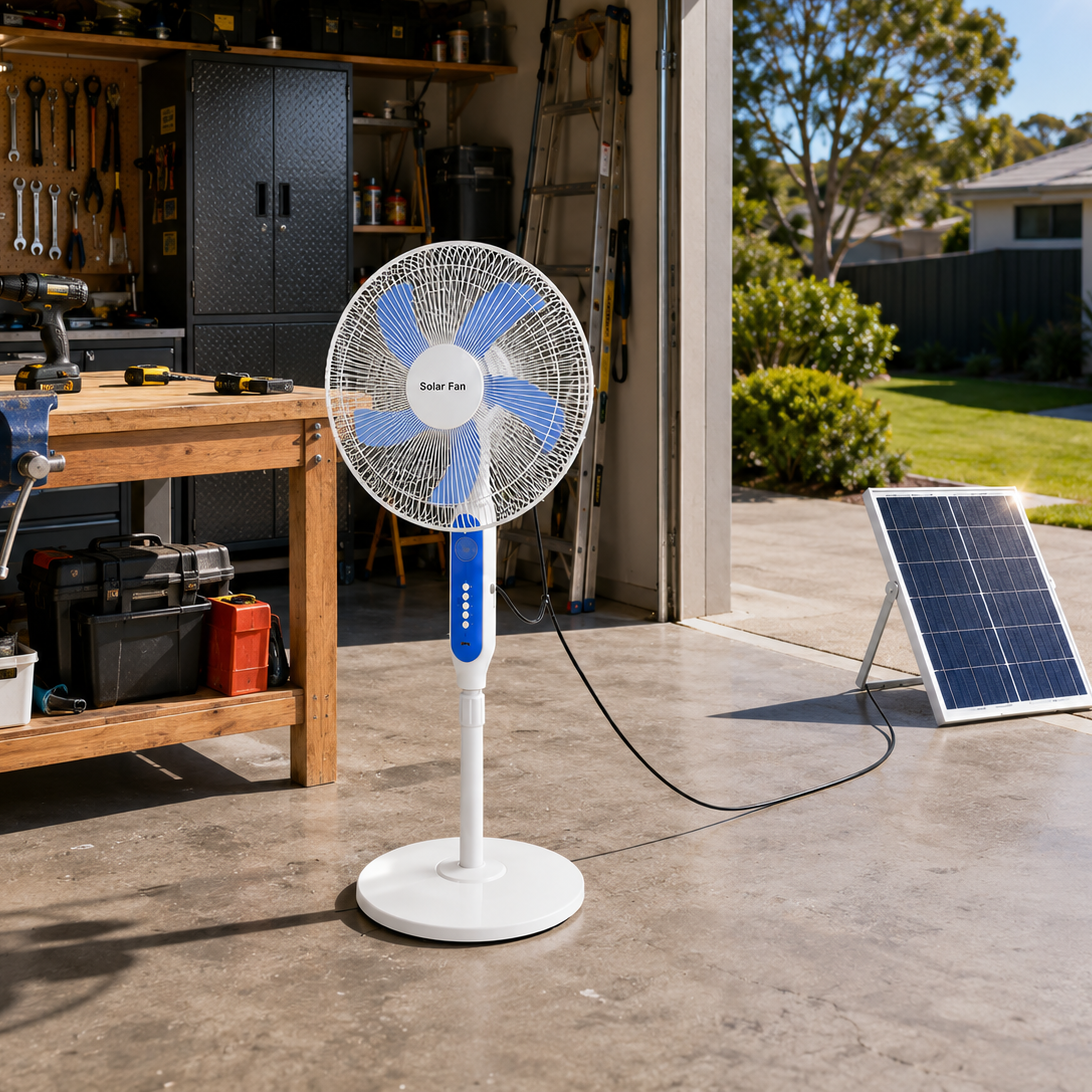 A white and blue solar powered stand fan providing ventilation inside a home garage workshop, running off its solar panel placed on the sunny driveway outside.