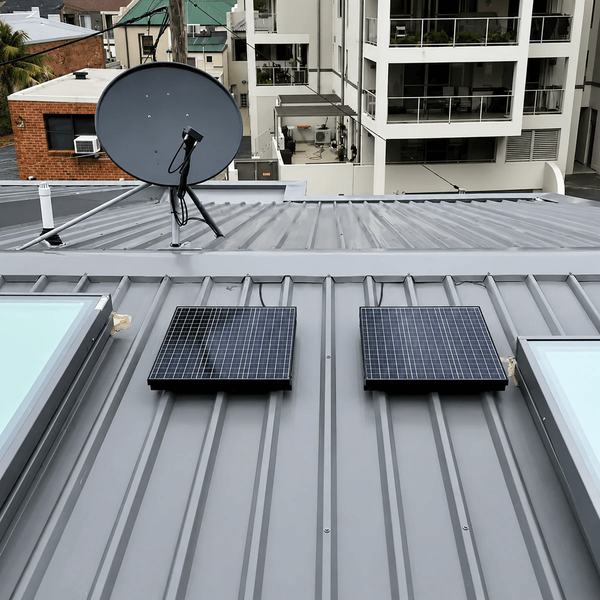 Two 40W polycrystalline solar panels installed flush on a grey corrugated metal Colorbond roof next to existing skylights, providing a clean solar skylight alternative system setup for an Australian home.