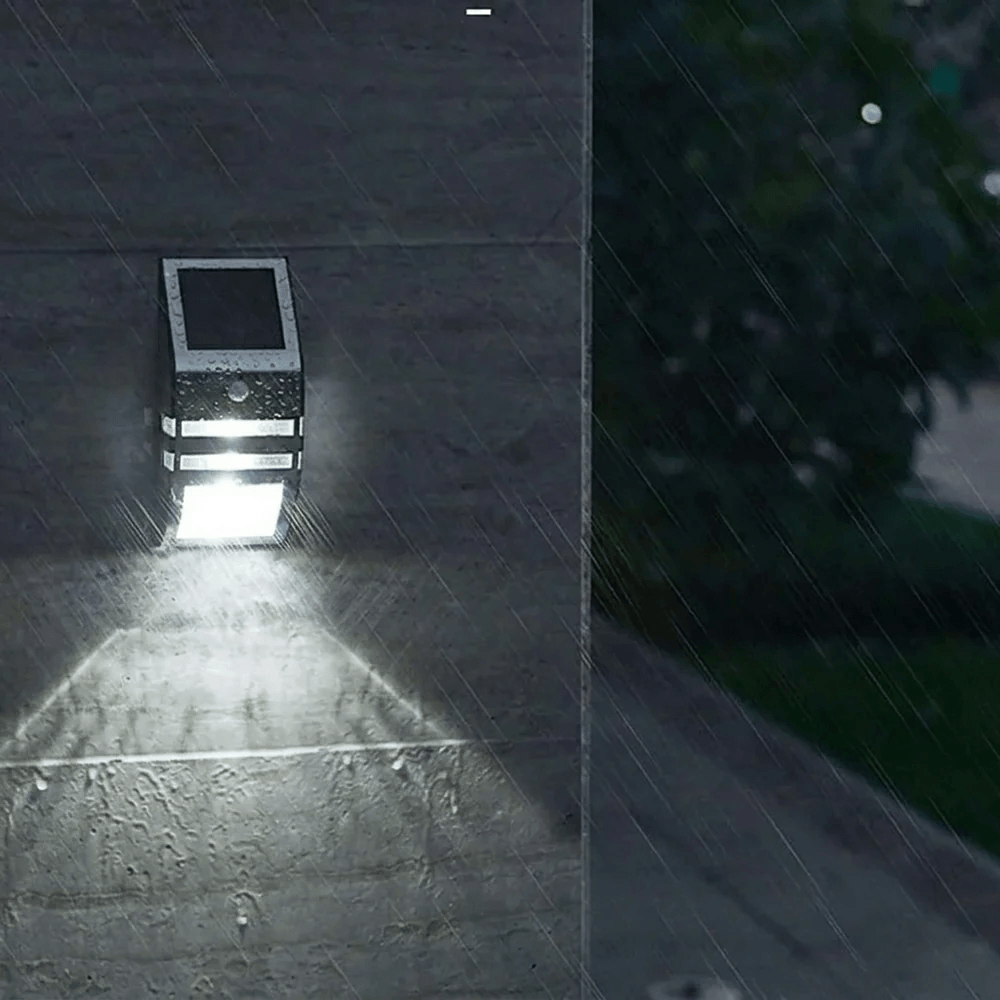 A waterproof solar wall light emitting a bright downward beam during a heavy night rain storm on an exterior stone wall.